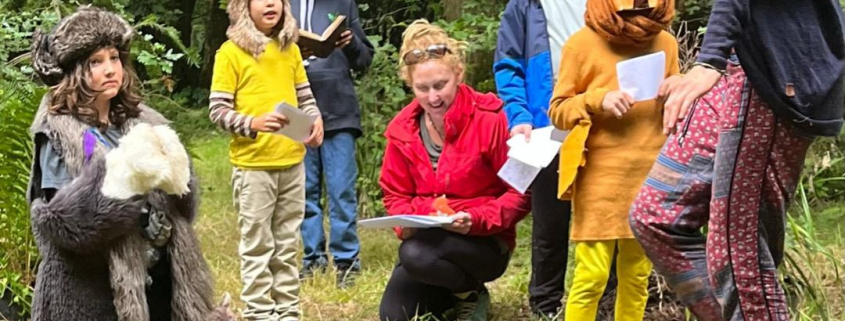 Children in brightly coloured cothes and hand-made animal costumes, reciting a play in the forest with their teacher, looked on by their parents