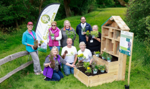 A group of people displaying a pollination education station otherwise known as a luxury bug hotel