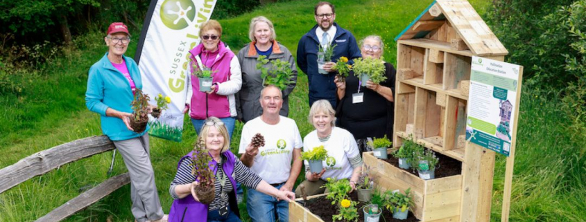 A group of people displaying a pollination education station otherwise known as a luxury bug hotel